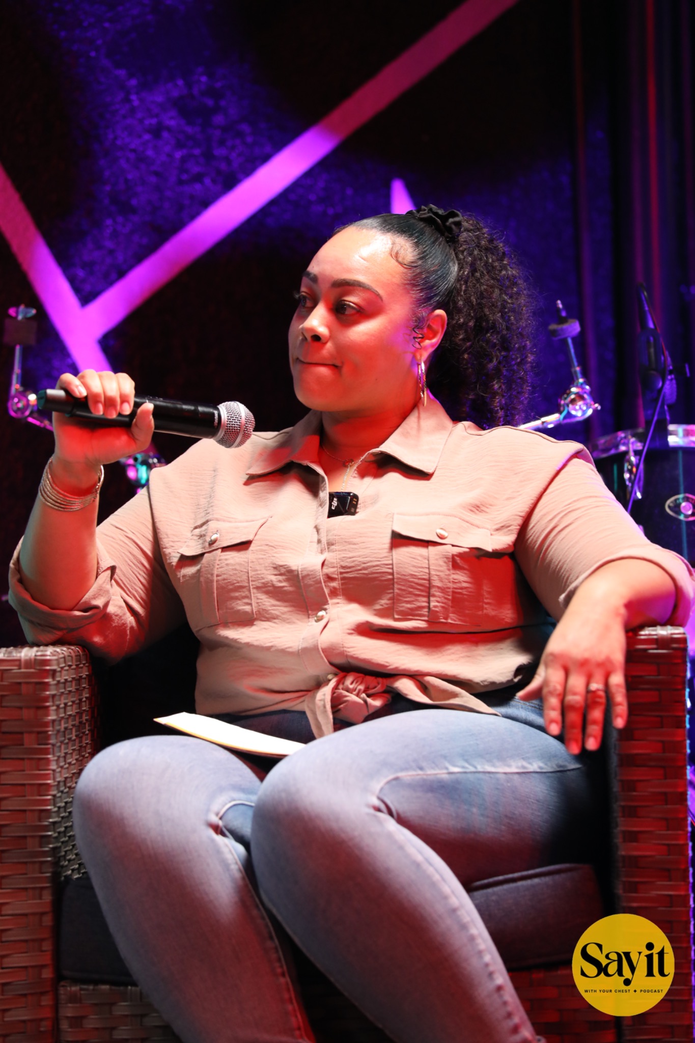 A panelist holding a microphone under the colorful stage lights